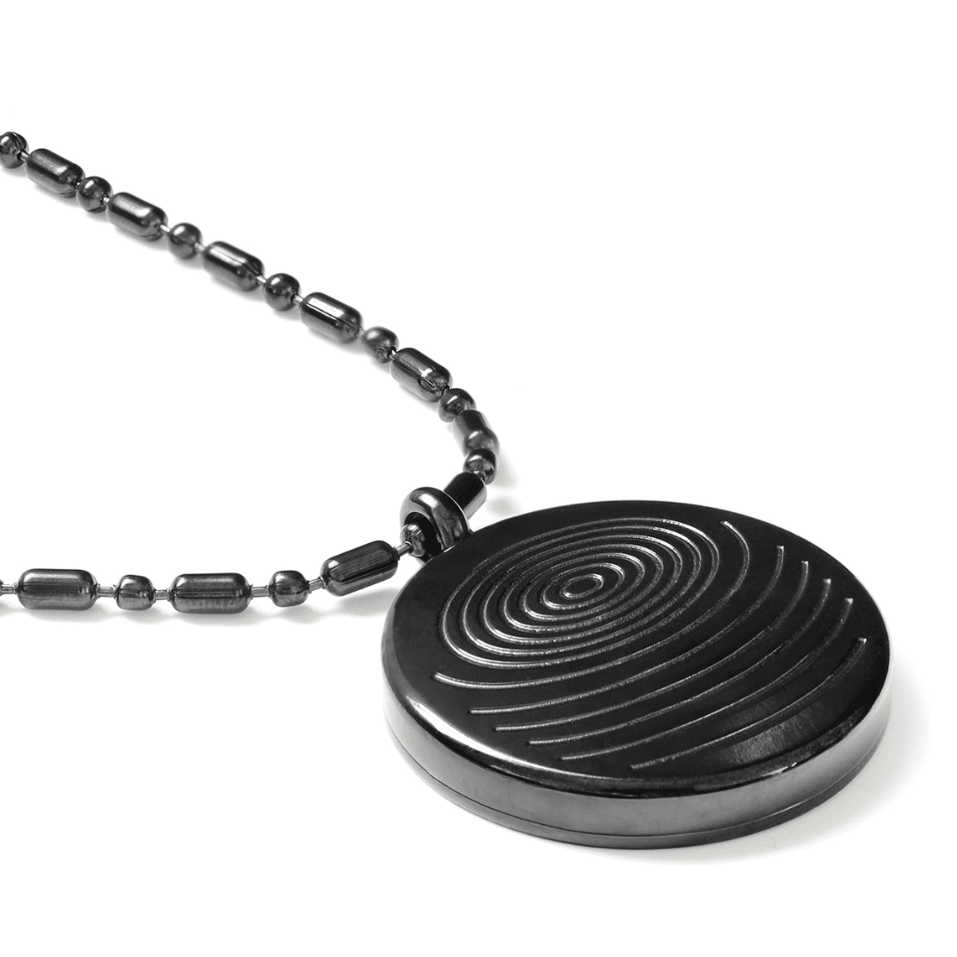 A close-up of a circular defense pendant with a black textured disc and matching black beaded chain displayed on a clean white background, highlighting surface detail and finish. — for Carpe Diem Dream