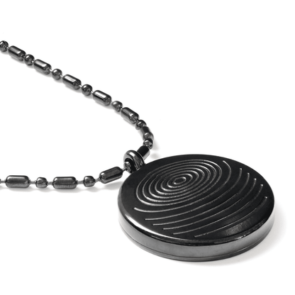 A close-up of a circular defense pendant with a black textured disc and matching black beaded chain displayed on a clean white background, highlighting surface detail and finish. — for Carpe Diem Dream