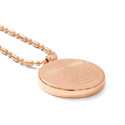A close-up of a circular defense pendant with a rose gold textured disc and matching rose gold beaded chain displayed on a clean white background, highlighting surface detail and finish. — for Carpe Diem Dream