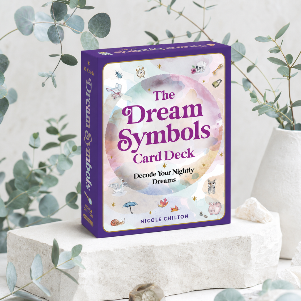 The Dream Symbols Card Deck box in a cool-toned studio botanical setting with eucalyptus, soft mauve textile, and ceramic accents — for Carpe Diem Dream.