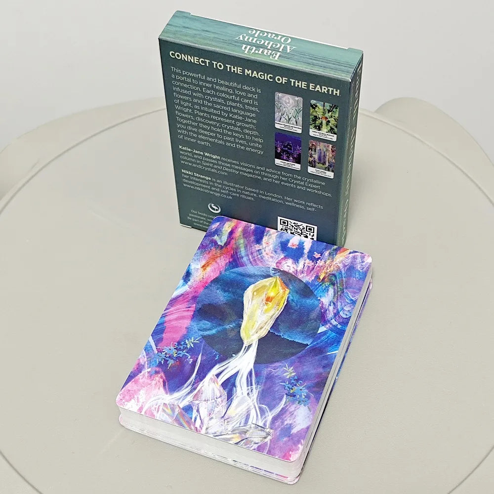The Earth Alchemy Oracle deck is shown stacked with its illustrated cards beside the upright box packaging on a neutral surface, displaying the full set and design. — for Carpe Diem Dream