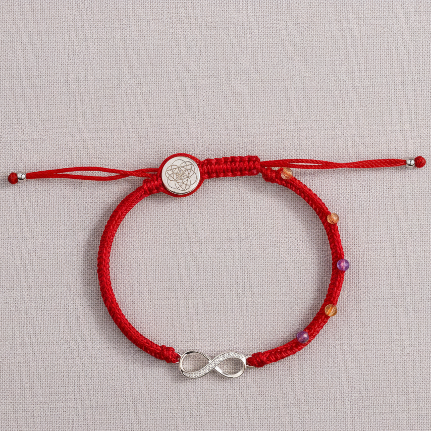 Red string bracelet with sterling silver infinity charm displayed on a textured neutral backdrop under soft natural lighting. — for Carpe Diem Dream