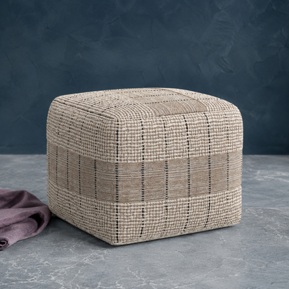 Elmer handwoven jute and cotton square pouf in natural and gray photographed on a cool stone surface with a mauve textile accent. — for Carpe Diem Dream