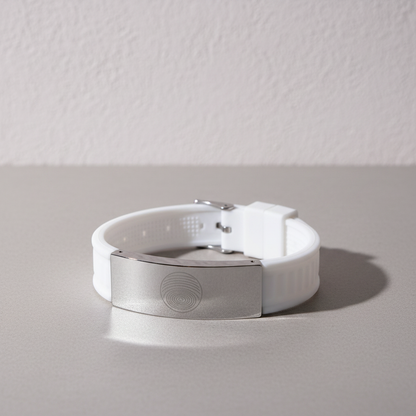 White EMF defense bracelet with stainless steel plate displayed on a clean neutral surface against a softly textured wall with gentle natural lighting and shadow. — for Carpe Diem Dream