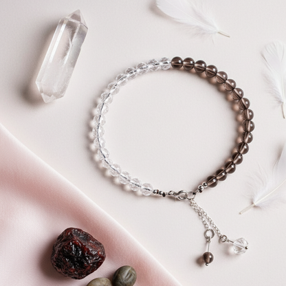 Smoky Quartz and Clear Quartz anklet displayed on soft blush fabric with scattered feathers and gemstones. — for Carpe Diem Dream