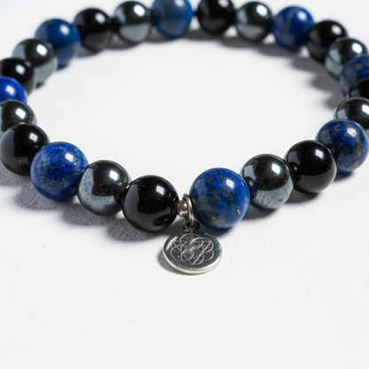 Lapis lazuli, onyx, and hematite gemstone bracelet with silver charm displayed on white surface in soft light. — for Carpe Diem Dream