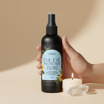 Hand holding Evil Eye Protection ritual spray bottle beside a candle and clear quartz crystal showing the size of the 4 oz bottle. — for Carpe Diem Dream