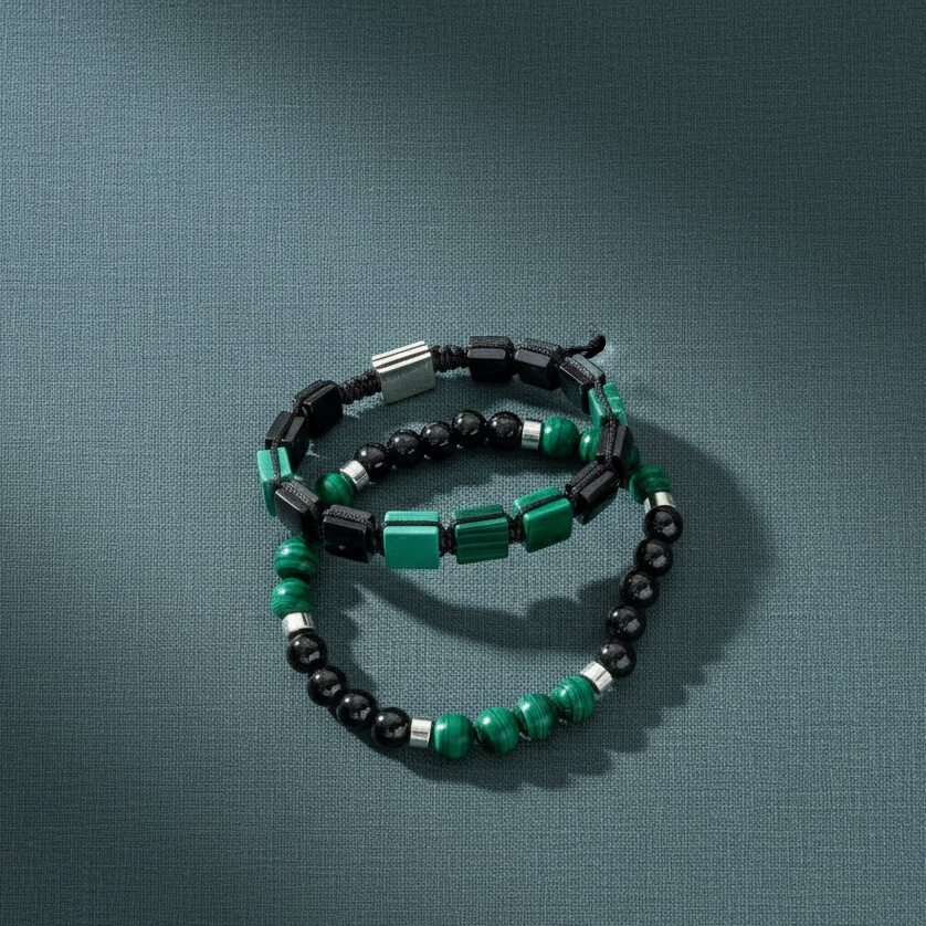 A malachite and black tourmaline bracelet set arranged in a circular form on a dark textured surface, illuminated with soft directional light. — for Carpe Diem Dream