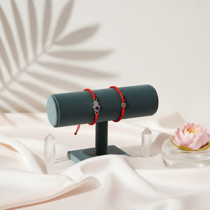 Red string bracelet with a silver Hamsa charm and crystal displayed on a velvet jewelry stand with silk draping and soft botanical shadows. — for Carpe Diem Dream