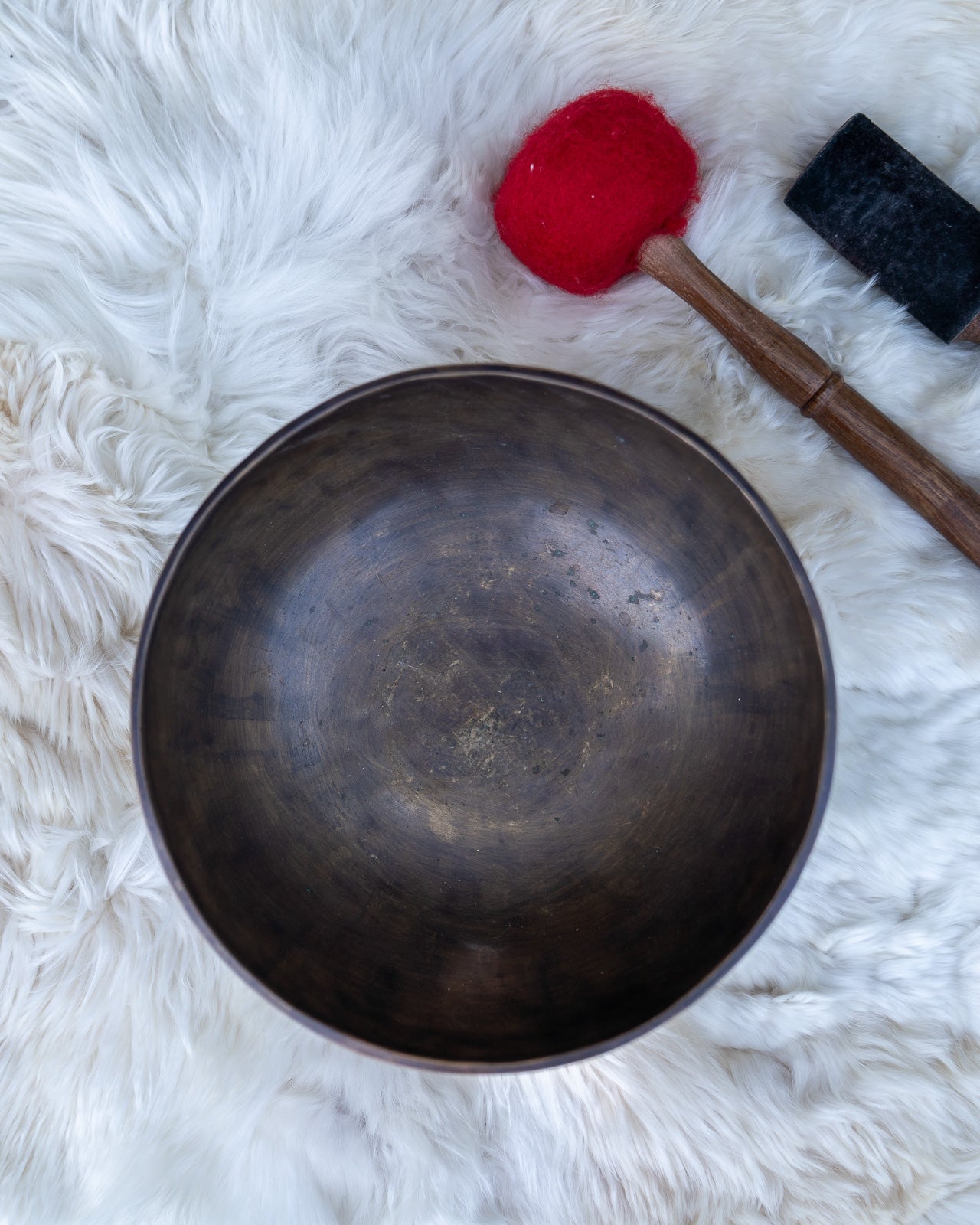 Top view of a hand-hammered Tibetan singing bowl showing the interior surface resting on an embroidered cushion. — for Carpe Diem Dream