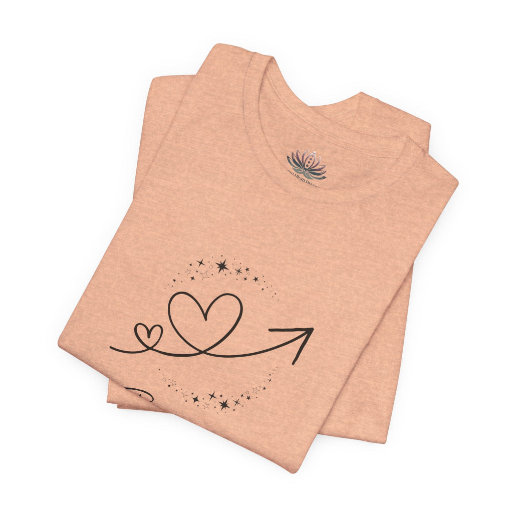 Gemini Rising I Engage zodiac T-shirt in Heather Peach with black celestial heart and arrow artwork, shown folded in a supplier mockup. — for Carpe Diem Dream