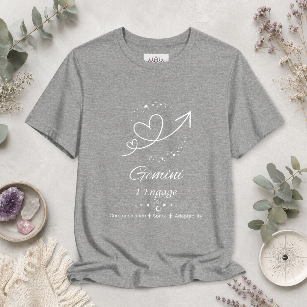 Gemini Rising I Engage zodiac T-shirt in Athletic Heather with white celestial heart and arrow artwork and Communication, Spark, Adaptability text, styled in a cool-toned studio botanical flat lay. — for Carpe Diem Dream