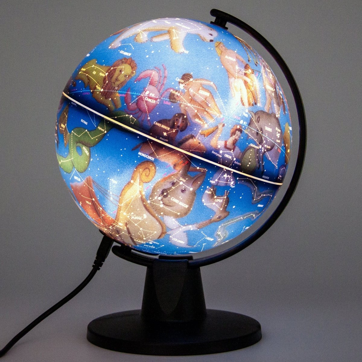 Illuminated six inch constellation globe displaying zodiac illustrations glowing in a dark room on a black stand with visible USB cord — for Carpe Diem Dream