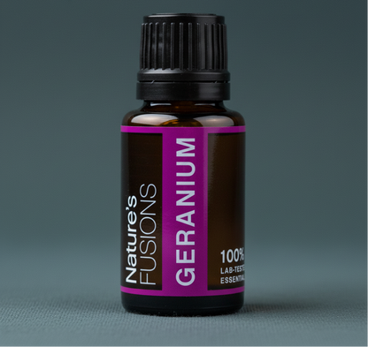 Close-up of a 15ml amber glass bottle of Geranium essential oil with a black cap and magenta label against a muted teal background. — for Carpe Diem Dream