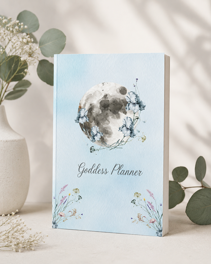 Goddess Planner paperback displayed in a botanical-inspired sanctuary setting with layered textiles, fresh greenery, and moon-inspired accents, supporting lunar reflection, self-care rituals, mindful planning, and intentional living. — for Carpe Diem Dream