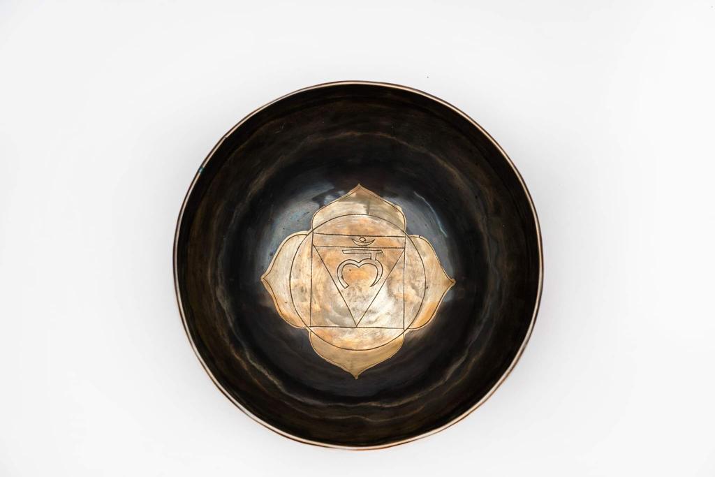 Top view of a black ceramic singing bowl with a gold chakra mandala design on a white background. — for Carpe Diem Dream