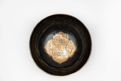 Top view of a black ceramic singing bowl with a gold chakra mandala design on a white background. — for Carpe Diem Dream
