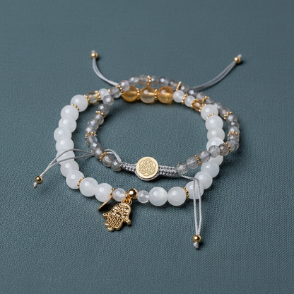 A set of crystal bracelets featuring citrine, moonstone, and labradorite beads with gold accents and a hand of hamsa charm displayed on a muted teal background. — for Carpe Diem Dream