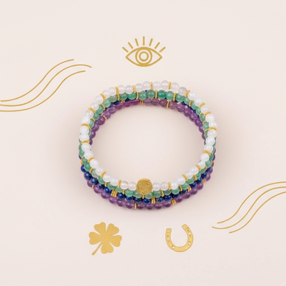 Multicolored gemstone luck bracelets displayed in a circle on soft cream surface with gold symbolic illustrations. — for Carpe Diem Dream