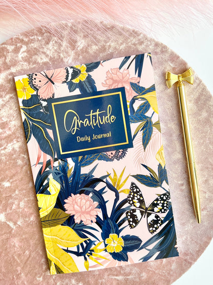 Floral Gratitude Daily Journal in glossy softcover format displayed on a blush velvet surface with a gold pen beside it — for Carpe Diem Dream