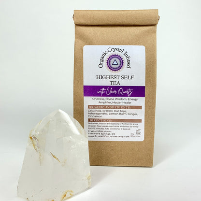 Highest Self Tea – Organic Crystal Infused 50g loose-leaf herbal tea with Clear Quartz crystal energy, displayed beside a polished Clear Quartz point on a clean white background. — for Carpe Diem Dream