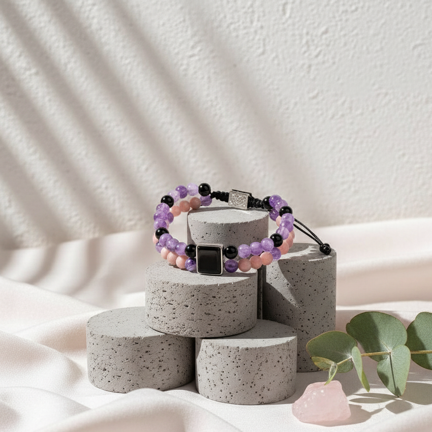 Feminine power healing bracelet in amethyst, pink opal, and onyx displayed on stacked stone pedestals with soft diffused studio lighting — for Carpe Diem Dream