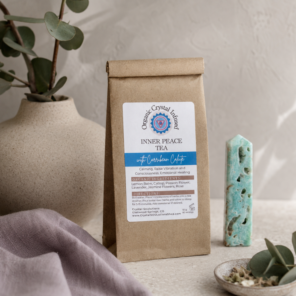 Inner Peace Tea – Organic Crystal-Infused Herbal Tea with Carribean Calcite displayed in the Carpe Diem Dream Botanical Studio on natural stone with Roman Clay walls, eucalyptus, matte ceramics, mauve linen, and soft cool diffused daylight. The authentic product remains the focal point within a refined quiet-luxury botanical setting. — for Carpe Diem Dream