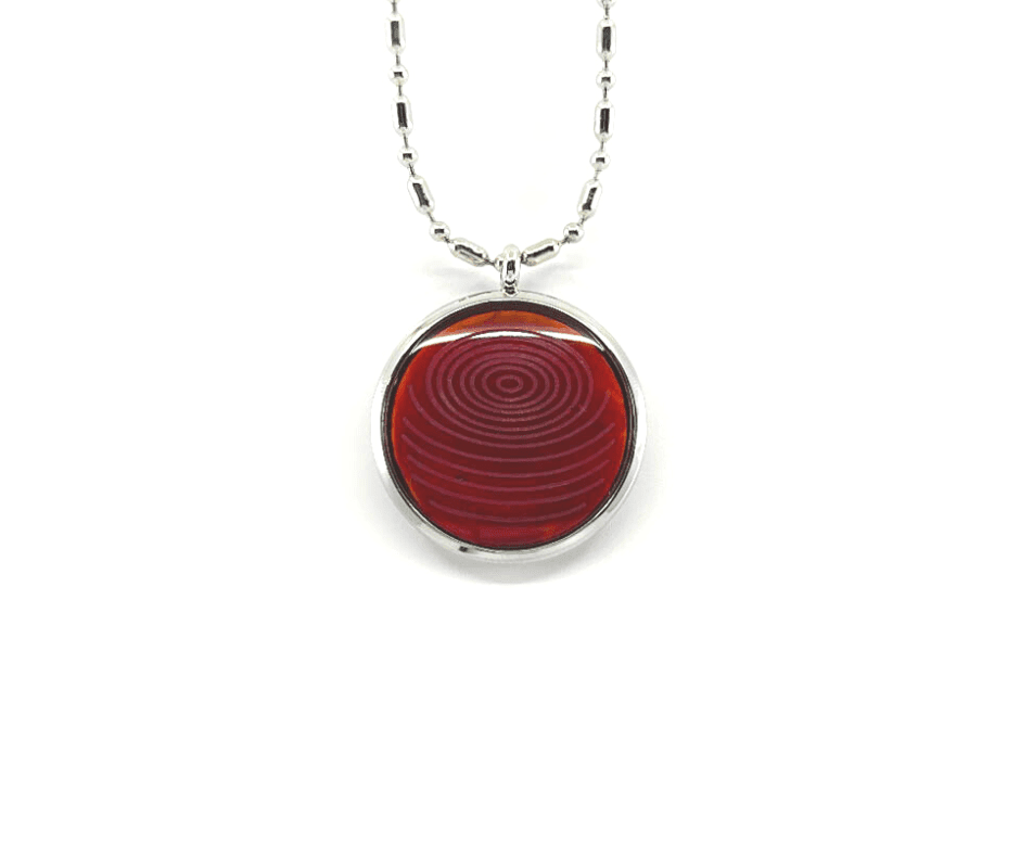 A rose coral ion glass defense pendant with a spiral design on a silver chain, displayed on a white background. — for Carpe Diem Dream