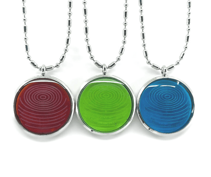 Three ion glass defense pendants with spiral designs in red, green, and blue, displayed side by side on silver chains against a white background. — for Carpe Diem Dream