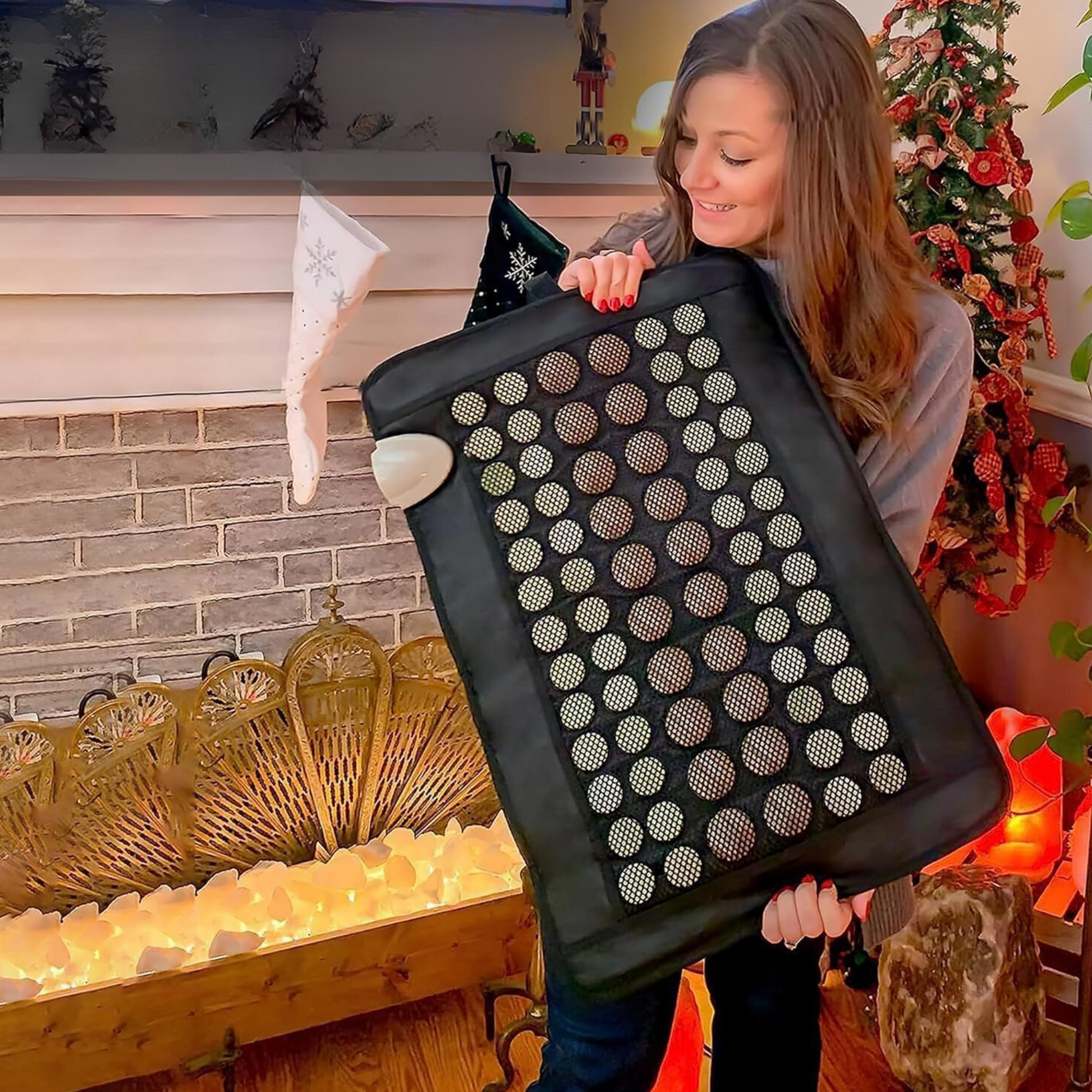 Woman holding a jade and tourmaline far infrared heating pad showing the full size of the mat in a home setting. — for Carpe Diem Dream