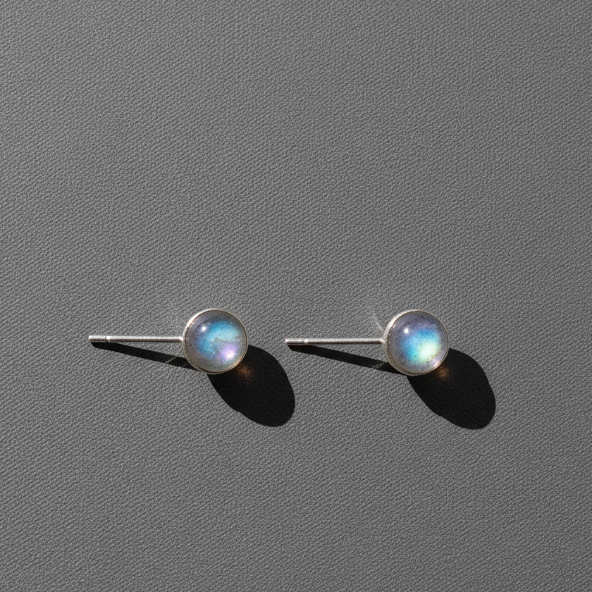 Silver labradorite stud earrings resting on a softly textured studio background. — for Carpe Diem Dream