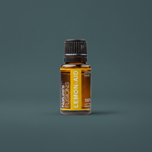 A 15ml amber glass bottle of Lemon-Aid uplifting citrus essential oil with a black cap and yellow label displayed against a muted teal background — for Carpe Diem Dream