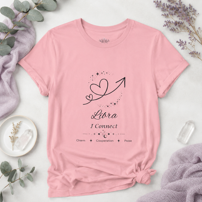 Libra Rising I Connect zodiac T-shirt in pink with black celestial heart and arrow artwork and Charm, Cooperation, Poise text, styled in a cool-toned studio botanical flat lay. — for Carpe Diem Dream