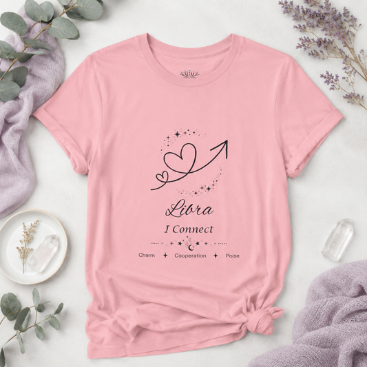 Libra Rising I Connect zodiac T-shirt in pink with black celestial heart and arrow artwork and Charm, Cooperation, Poise text, styled in a cool-toned studio botanical flat lay. — for Carpe Diem Dream