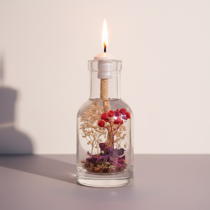 A Libra zodiac oil candle with red and white botanicals in a clear glass vessel burns with a soft flame against a neutral background with gentle shadow. — for Carpe Diem Dream