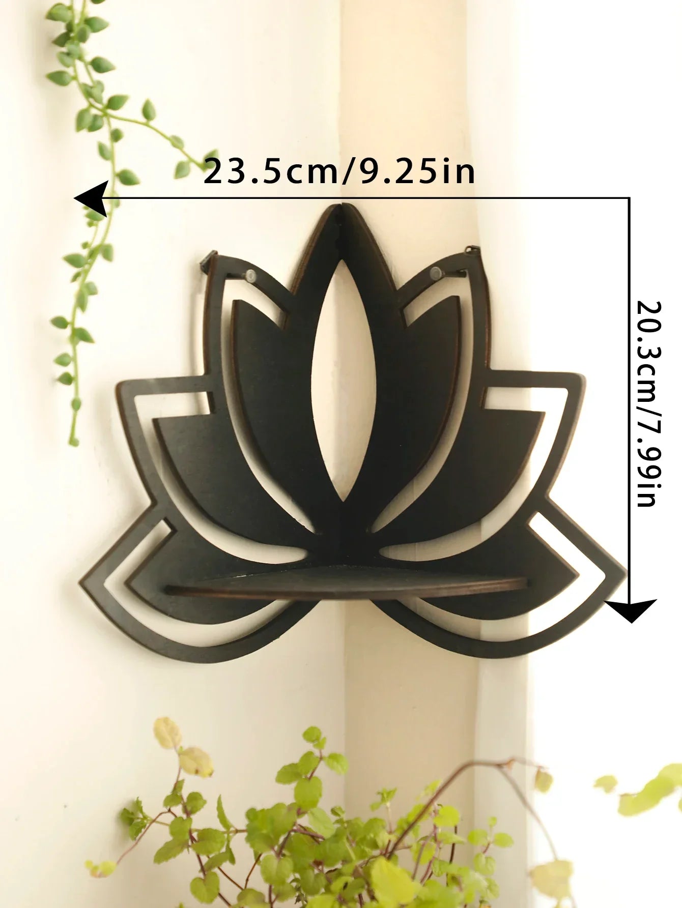 A black lotus-shaped wall shelf mounted on a wall with visible dimensions labeled approximately 23.5 cm wide and 20.3 cm tall with greenery surrounding the scene. — for Carpe Diem Dream