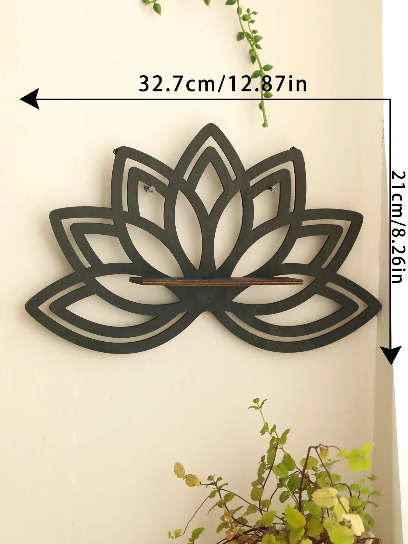 A black lotus-shaped wall shelf mounted on a wall with visible dimensions labeled approximately 32.7 cm wide and 21 cm tall with greenery in the scene. — for Carpe Diem Dream