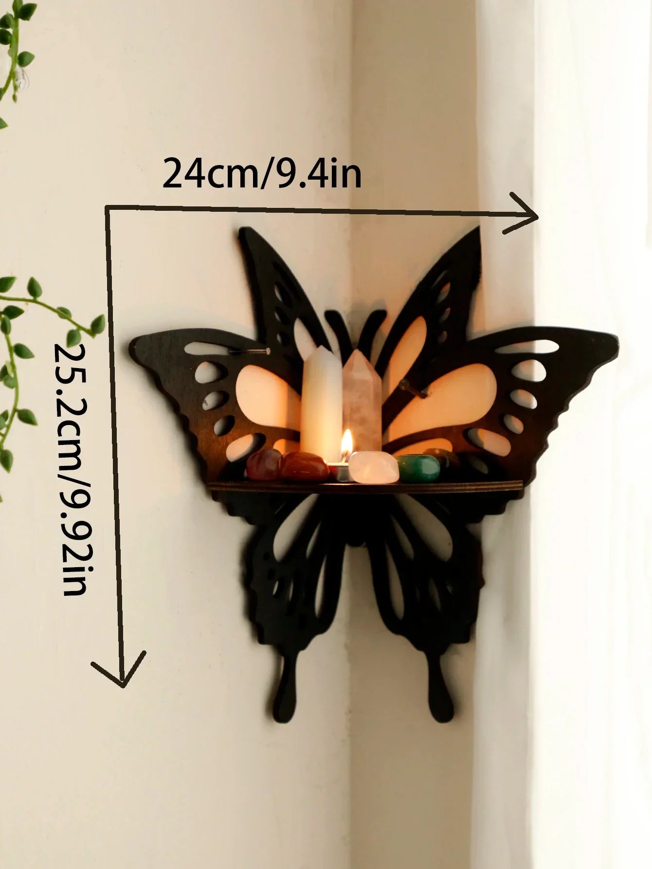 A black butterfly-shaped wall shelf mounted in a corner with visible dimensions labeled approximately 24 cm wide and 25.2 cm tall, displaying candles and small decorative items. — for Carpe Diem Dream
