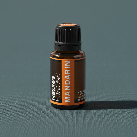 Amber glass bottle of Mandarin Essential Oil standing upright on muted teal textured background with soft directional shadow. — for Carpe Diem Dream
