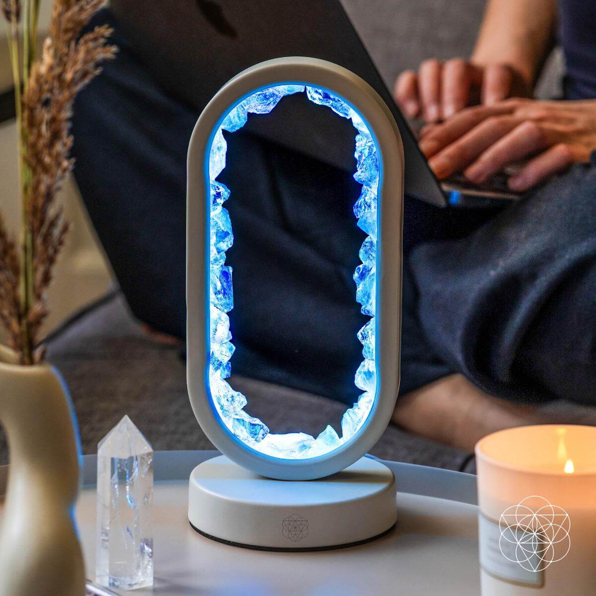 Decorative lamp with blue light on a table next to a person using a laptop.