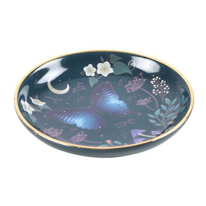 Angled view of the Midnight Moth Celestial Trinket Dish showcasing a blue night sky design with a moth, moon, and floral details, finished with gold edging, styled for Carpe Diem Dream.