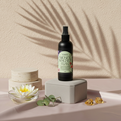 Money Magnet Smudge Spray bottle displayed on neutral stone risers with lotus flower, eucalyptus leaves, and soft botanical shadows on a textured wall. — for Carpe Diem Dream