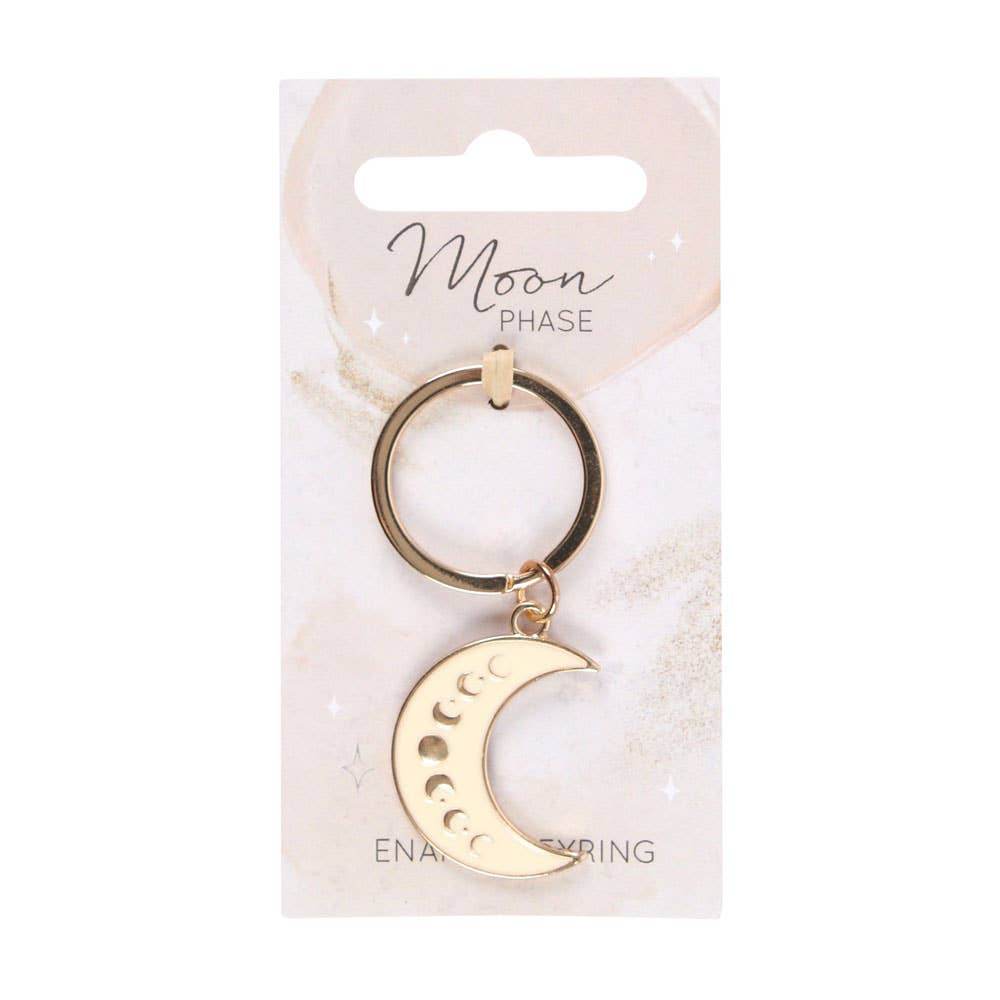 Moon Phase Celestial Keychain featuring an enameled gold crescent moon charm with lunar phase design, displayed on a white branded backing card under soft neutral lighting for Carpe Diem Dream.