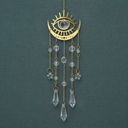 Gold moon phase crystal sun catcher with crescent moon, eye design, and hanging faceted crystals displayed against a deep teal linen background. — for Carpe Diem Dream