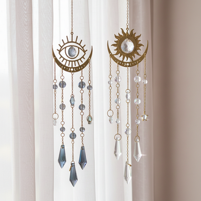 Two moon phase crystal sun catcher variants displayed side by side, featuring Moon Eyes and Moon Sun designs with gold metal and hanging crystals. — for Carpe Diem Dream