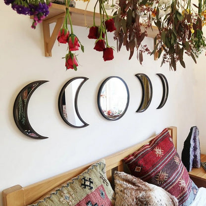 Black five-piece moon phase wall mirror set displayed above a bed with patterned pillows, dried hanging flowers, and crystals in a boho bedroom setting. — for Carpe Diem Dream