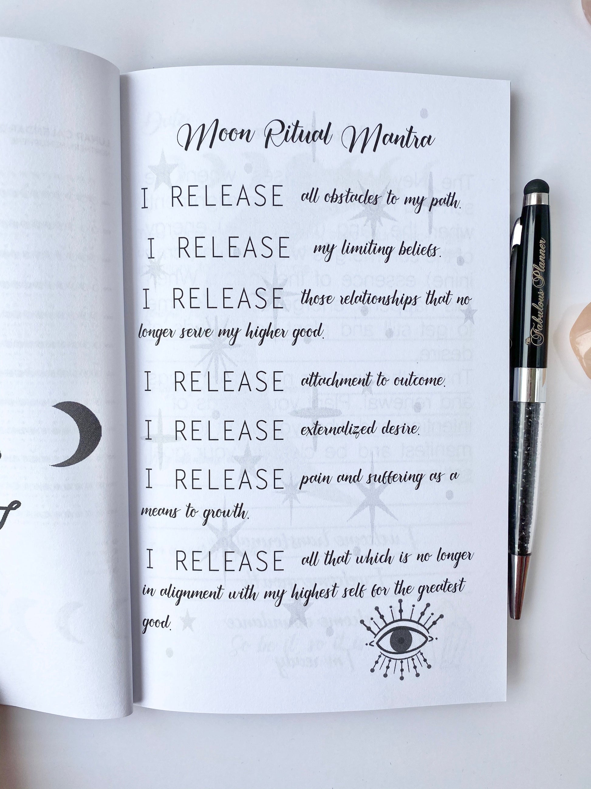 Interior spread of Moon Rituals & Manifestation Journal showing Moon Ritual Mantra page with guided affirmation text and lunar graphics beside a pen on a white background — for Carpe Diem Dream