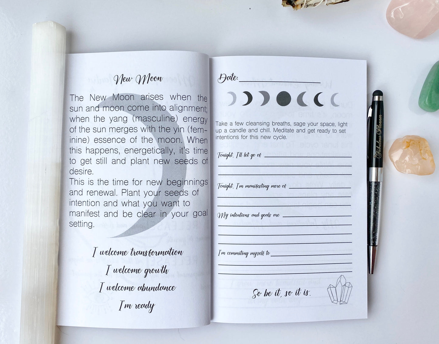 Interior spread of Moon Rituals & Manifestation Journal showing New Moon intention setting page with lunar phase graphics, guided prompts, and lined writing sections beside a pen on a white background — for Carpe Diem Dream
