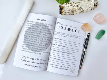 Interior spread of Moon Rituals & Manifestation Journal showing Full Moon reflection page with lunar phase graphics, guided prompts, and lined writing sections beside a pen and crystals on a white background — for Carpe Diem Dream