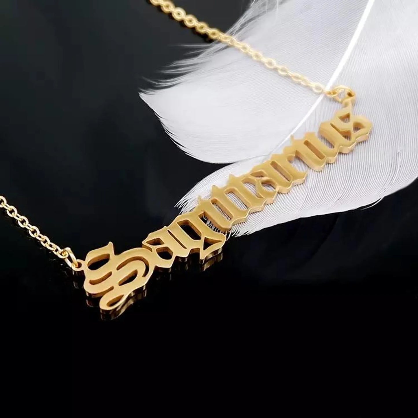 Gold Old English Zodiac Sagittarius Necklace with astrology lettering on black background with white feather for Carpe Diem Dream